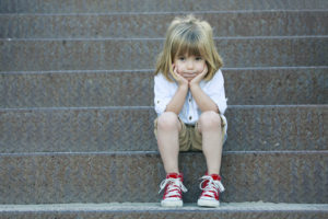 Sad little boy sitting on staircase.