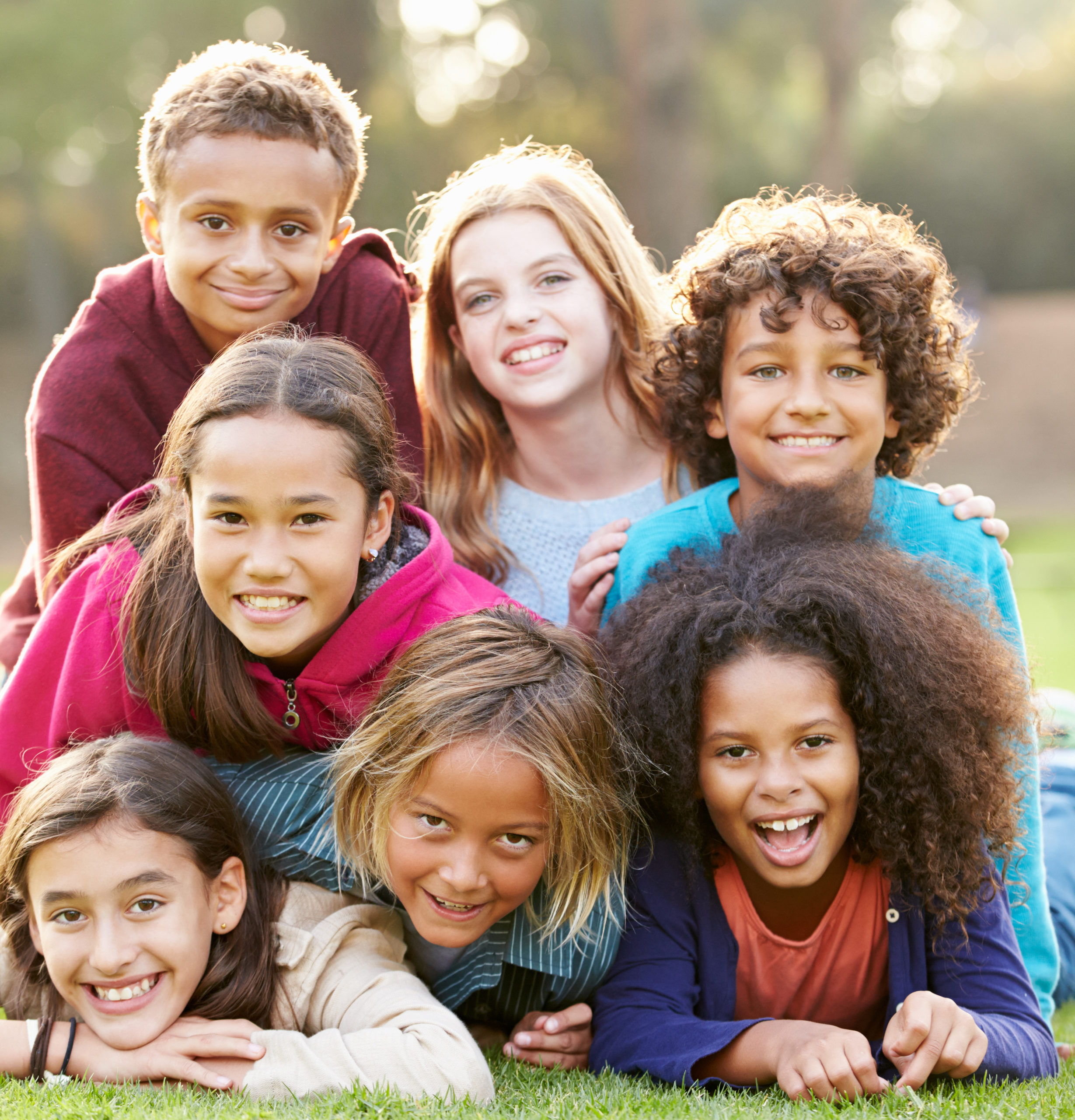 Group Of Children Lying On Grass Together In Park Group Of Children Lying On Grass Together In Park Smiling To Camera